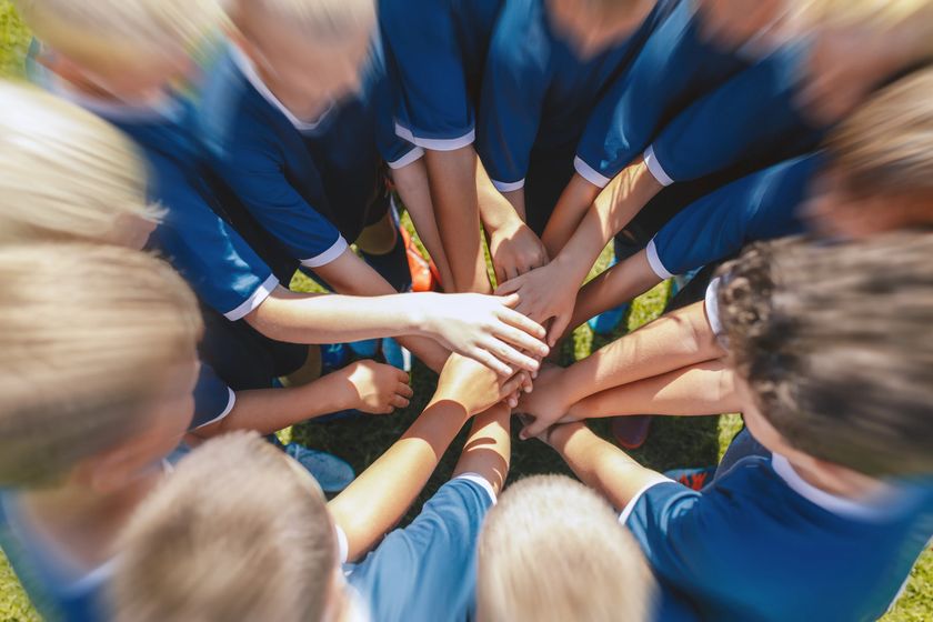 A youth sports team stacking their hands together in a huddle