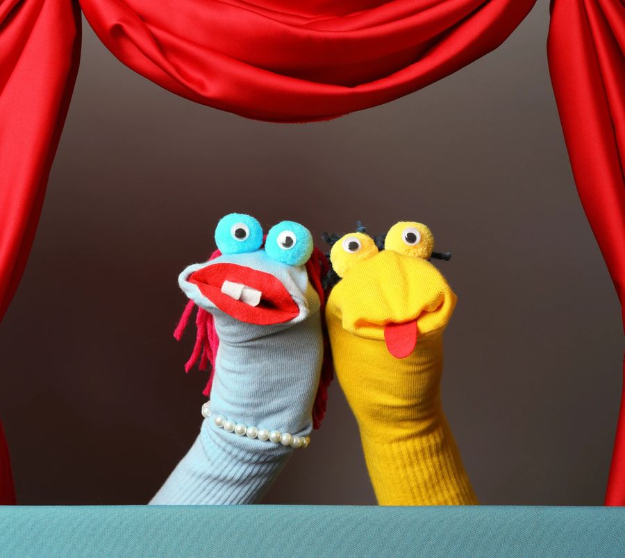 Sock puppets on a small stage framed by red curtains