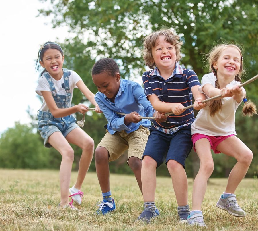 Children playing tug of war together on a sunny field