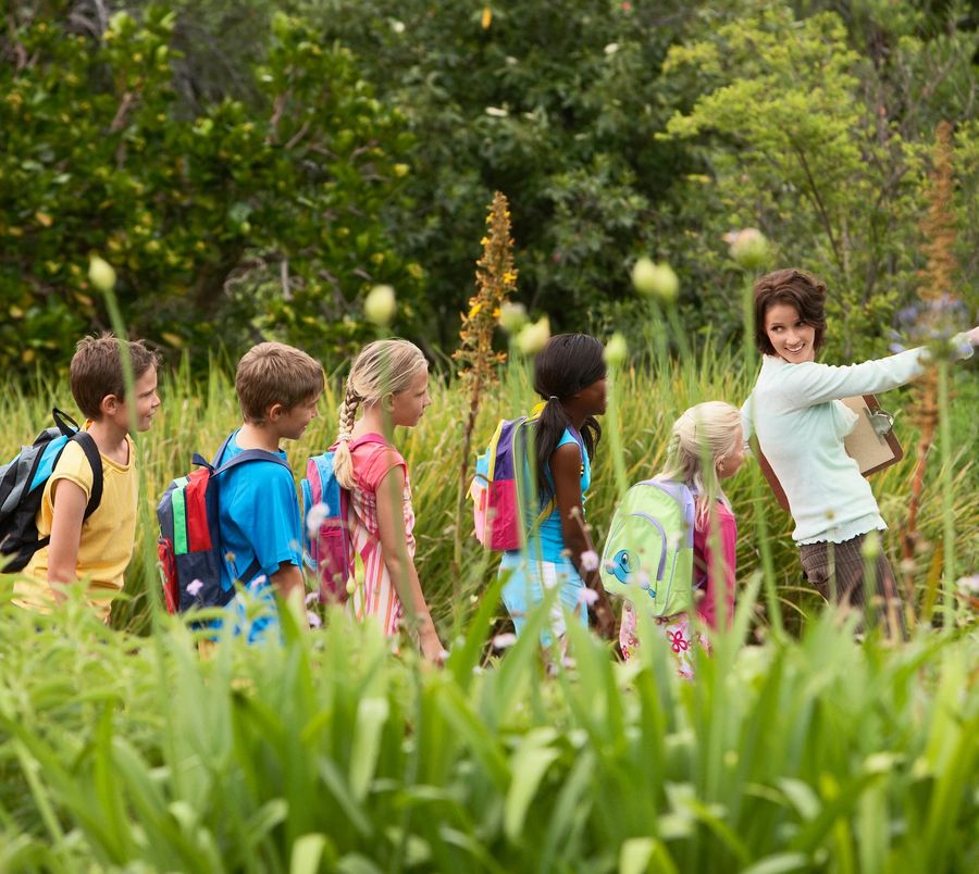 An event leader guiding a line of children along a nature trail