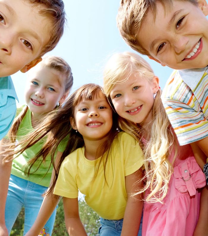 A group of children smiling together in the sunshine