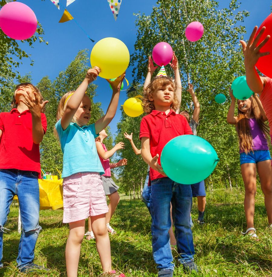 Children throwing balloons in the air at an outdoor party