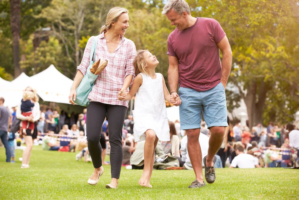 Parents and their daughter walking together at an outdoor event